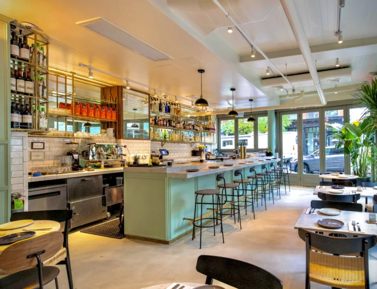 nterior design of Shoo Shoo Nolita restaurant featuring a copper ceiling, hanging plants, and warm wood accents.